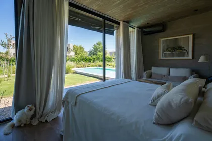 Dormitorio moderno con vistas a piscina y jardín — proyecto Casa Tres Patios, por Besonías Almeida arquitectos, en Pilar