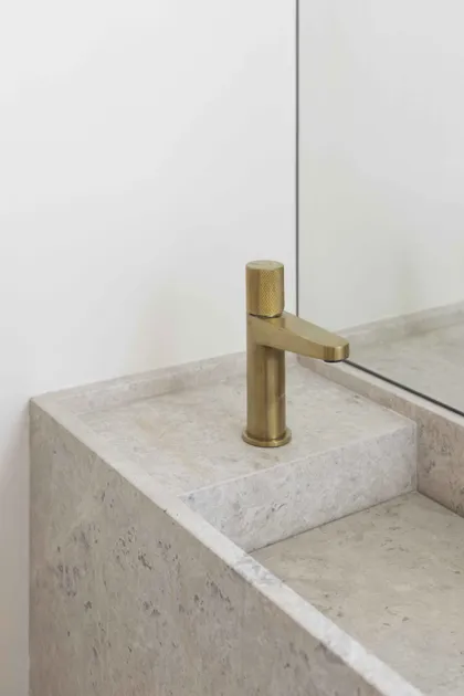 Baño moderno con lavabo de piedra y grifería de latón — proyecto Libertador, por Bouré Studio, en Palermo