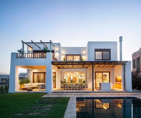 Fachada moderna con pérgola de madera y piscina iluminada — proyecto Casa Ibiza, por MUCHTEK, en Barrio Santa Ana