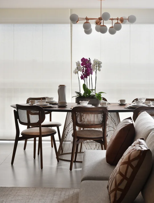Comedor moderno con sillas de rattan, mesa oscura y orquídea púrpura — proyecto Apartamento DE, por Giovana Ciacco, en Guarulhos