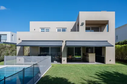 Fachada moderna con piscina y pérgola — proyecto Campo grande IV, por Juarez-Fevre Estudio de Arquitectura , en Buenos Aires