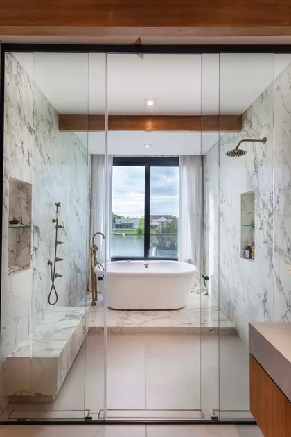 Baño moderno con bañera exenta y vistas al exterior — proyecto Los Castores, Nordelta, por Build a Home Arquitectura, en Nordelta
