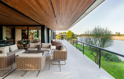 Terraza moderna con muebles de rattan y vista al rio — proyecto Casa Porsche, por Remy Arquitectos, en Buenos Aires