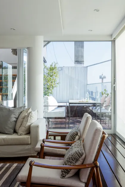 Terraza moderna con sillones estilo mid-century y vista urbana — proyecto Piso en Libertador III, por Gutman+Lehrer Arquitectas, en CABA