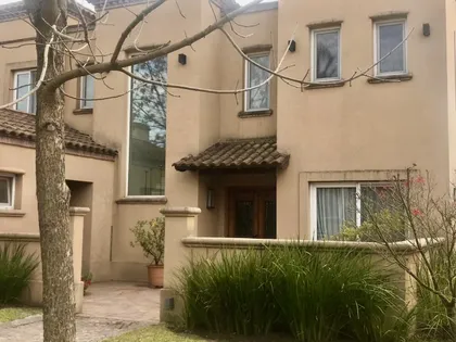 Fachada residencial estilo mediterráneo con ventanas grandes y pérgola de madera — proyecto Los Galapagos Garín, por Marconi Silva Arquitectos, en Garin