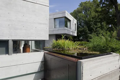 Fachada moderna de hormigón con vegetación integrada y espejo de agua — proyecto Acasusso, por Remy Arquitectos, en Acassuso