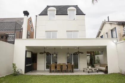 Fachada moderna con patio cubierto y comedor exterior — proyecto Casa Estilo Francés, por Estudio Fernandez Long & asoc., en Martínez