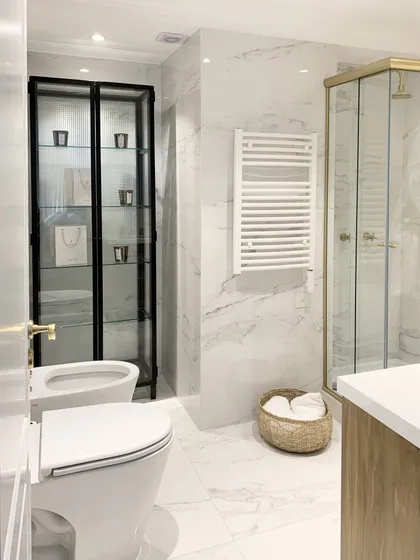 Baño moderno con mármol, detalles dorados y mueble exhibidor — proyecto QUINTANA, por Estudio Cést Moi, en Recoleta