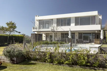 Casa contemporánea con fachada blanca, ventanales amplios y jardín frontal — proyecto Santa Barbara 121, por Build a Home Arquitectura, en B1648 Tigre