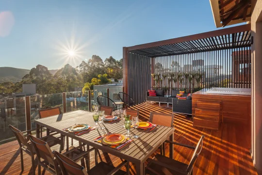 Terraza con deck de madera, comedor exterior y vistas a montaña — proyecto CASA RR, por Frederico Bicalho Arquitetura