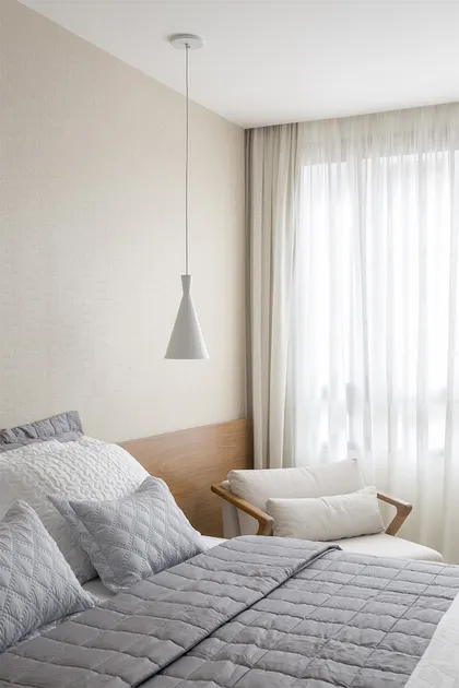 dormitorio minimalista con cama gris, lámpara colgante y cortinas blancas — proyecto Apartamento 108NW, por Coda Arquitetos