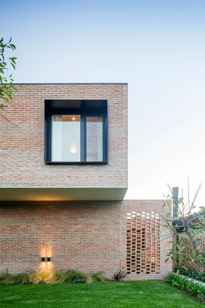 Fachada moderna de ladrillos expuestos con ventana minimalista y luz indirecta — proyecto Casa Brick, por LSA. , en Pilar