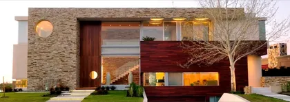 Fachada moderna de piedra y madera con grandes ventanales y detalles circulares — proyecto Casa Cinta, por Barrionuevo Arquitects, en B2814 Los Cardales