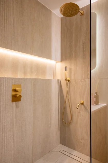 Baño moderno con ducha de latón, azulejos grandes y luz indirecta — proyecto ALVEAR TYM, por AB ARQUITECTURA, en Recoleta