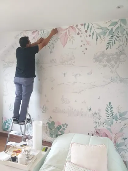 hombre instala mural botánico en pared de dormitorio — proyecto Habitacion campestre niñas, por Picma Empapelados, Murales, Esmerilados, Prints ,Papeles, en Canning