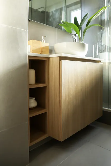 Baño moderno con vanitory flotante de madera clara y revestimiento de piedra gris — proyecto Jorge Newbery, por Estudio RG, en Belgrano