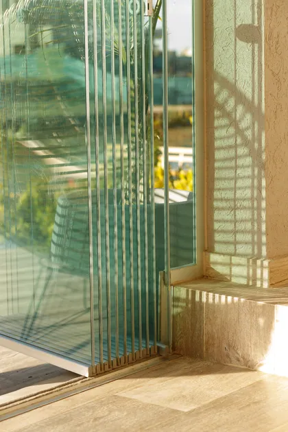 terraza con puertas plegables de vidrio y suelo de madera — proyecto TOLDER - CERRAMIENTOS, por Argentina en Obra 2024, en Rincón de Milberg