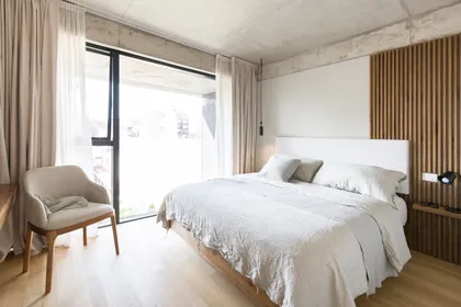Dormitorio moderno con ventanales, pared de listones de madera y cama grande — proyecto Nicaragua, por SRMD Arquitectura, en Palermo