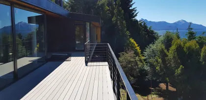 casa moderna con terraza de madera y vistas a la montaña — proyecto Casa Península San Pedro, por Servente Larrazabal Arq, en Bariloche