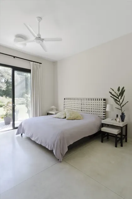 Dormitorio moderno con cama, ventana grande y suelo de cemento pulido — proyecto Casa M, por Estudio Dado, en Pilar