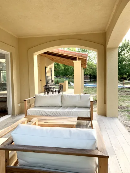 Patio exterior moderno con deck de madera y sillones blancos — proyecto Los Jazmines 2, por Marconi Silva Arquitectos, en Pilar
