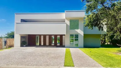Fachada moderna de casa con grandes ventanales y jardín — proyecto LRCC 245, por LESSI ARQUITECTURA, en Los Cardales