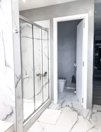 Baño moderno con ducha de vidrio y pisos de mármol — proyecto Nordelta , por Greschek Obras , en Nordelta