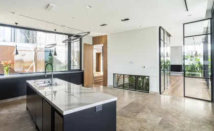 Cocina moderna de planta abierta con isla grande y ventanas de piso a techo — proyecto Casa CZ, por Estudio Juan Trivelloni