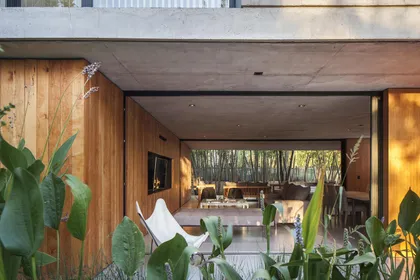 Fachada moderna con revestimiento de madera y silla mariposa — proyecto Casa MF, por V2 Arquitectos, en City Bell
