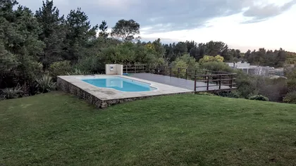 Piscina moderna rodeada de vegetación exuberante con deck de madera — proyecto Vivienda Unifamiliar en Costa Esmeralda, por Estudio Schifano, en Costa Esmeralda