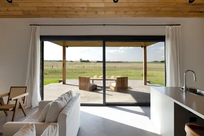Living moderno con ventanales grandes y techo de madera, vista a paisaje rural — proyecto Campo Cria , por Estudio Lak