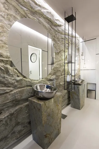 Baño moderno con paredes texturizadas de roca y lavabos metálicos sobre pedestales de mármol — proyecto Eclipse Lunar, por KUPERDESIGN CONSTRUCCIONES SRL, en B1636 Olivos