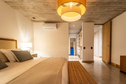 Dormitorio moderno con techo de hormigón visto y luz colgante natural — proyecto CASA sobre el MAR, por Guerrero Arquitectos, en Pinamar