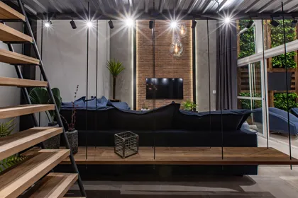 Living moderno con sofa negro, ladrillo visto y grandes ventanales — proyecto Duo Morumbi, por Pricila Dalzochio
