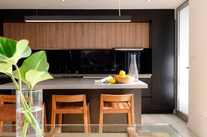 Cocina moderna con isla y muebles de madera, iluminación cálida — proyecto Guayra - Andrea Gonzales, por ABEJA CONCEPT, en Belgrano