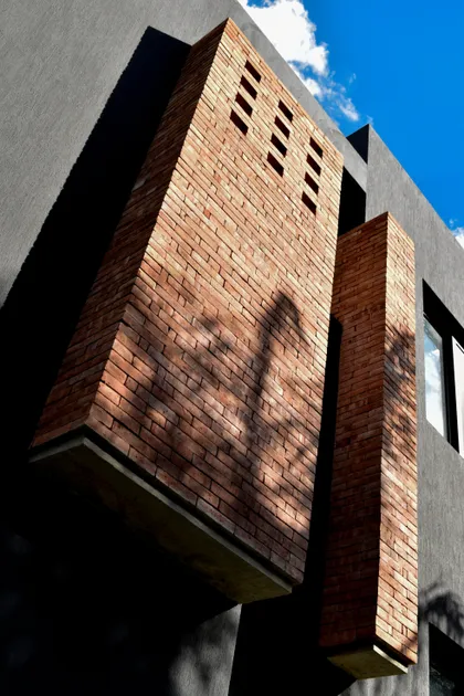 Fachada moderna de ladrillo y concreto con sombras — proyecto CASA HC, por Daniel Daniele - Oficina de Arquitectura, en Canning