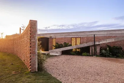 fachada moderna de ladrillos con muro curvo y detalles brutales — proyecto Casa Volt, por Estudio PK, en Capilla del Señor
