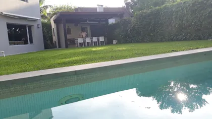 Piscina moderna con área de estar integrada y sector de comedor exterior — proyecto Obra Carlos Gardel, por Arq. Lourdes Yarade Saravia, en San Isidro