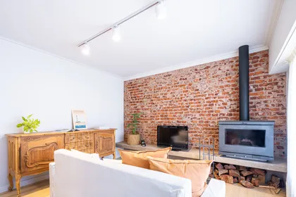 Living comedor con pared de ladrillo, mueble antiguo y chimenea moderna — proyecto REFROMA GUERNICA, por Maria Menna Arquitecta, en Mar del Plata