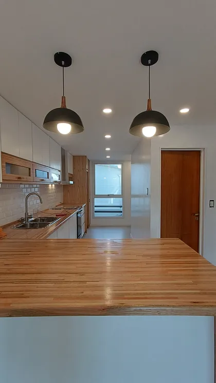 Cocina moderna estilo escandinavo con isla de madera y luces colgantes — proyecto PH LOZANO | Vivienda unifamiliar , por dariorivero.estudio, en Buenos Aires