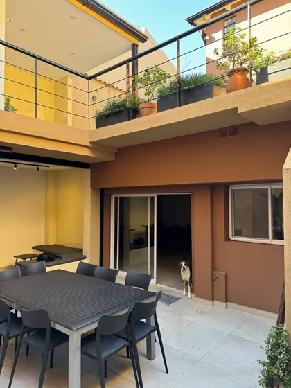 Patio moderno con mesa grande y perros en zona residencial — proyecto Marcelo & Majo, por Costantini studio, en Buenos Aires