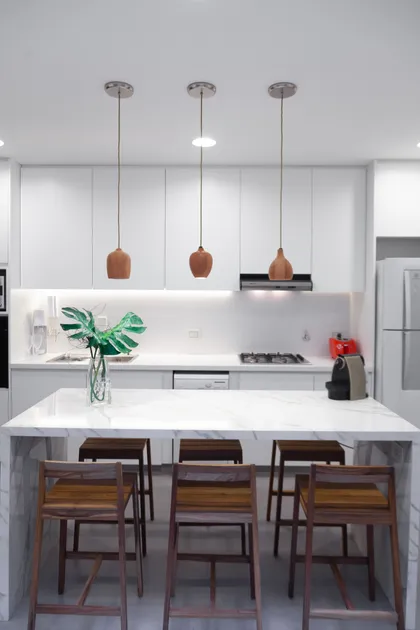 Cocina moderna con isla de mármol y taburetes, iluminación colgante — proyecto Obra Azcuenaga MI, por Arq. Lourdes Yarade Saravia, en Buenos Aires
