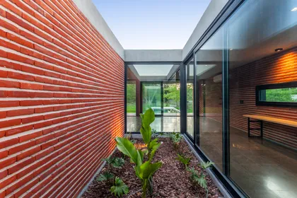 Patio moderno con muro de ladrillo visto y cristaleras — proyecto Casa FLOIG, por V2 Arquitectos, en Villa Elisa
