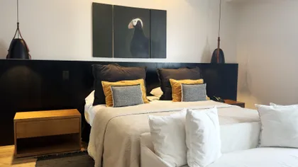 Dormitorio moderno con obra de arte de ave y luces colgantes — proyecto Villa Isidro Hotel Boutique & Spa, por Hermann Arquitectos, en San Isidro