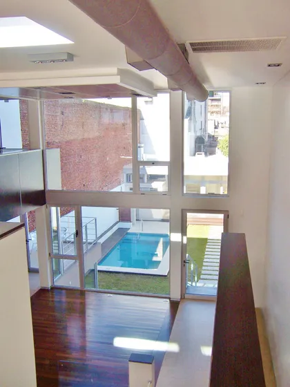 Living moderno con piscina interior y ventanas de piso a techo — proyecto Casa DF, por Santiago Cordeyro Arquitectos, en CABA