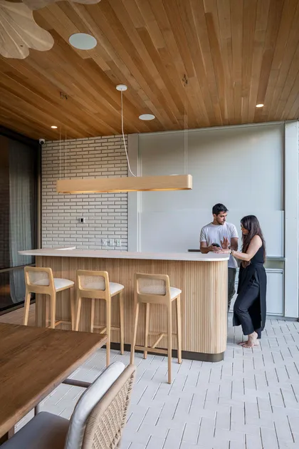 Bar moderno con luces lineales, banquetas de ratán y techo de madera — proyecto Casa Magnolia, por Estudio PK, en San Isidro