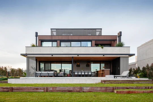 Casa moderna de hormigón y madera con amplios ventanales y terraza — proyecto Obra Wharehouse, por lifecycle, en B1648 Tigre