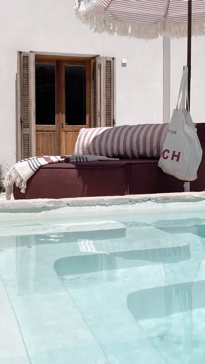 Sofá de exterior en piscina con textiles a rayas — proyecto El Refugio, por Grupo Pauta Arquitectura, en Pinamar