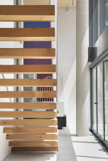 Escalera volada madera en hall luminoso con piso hormigón y ventanal — proyecto Stand Age 360, por GabrielaCasagrande Arquitetura