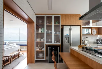 Cocina contemporánea con isla, muebles madera y vista al mar — proyecto APARTAMENTO VJ, por Marcia Debski Interiores